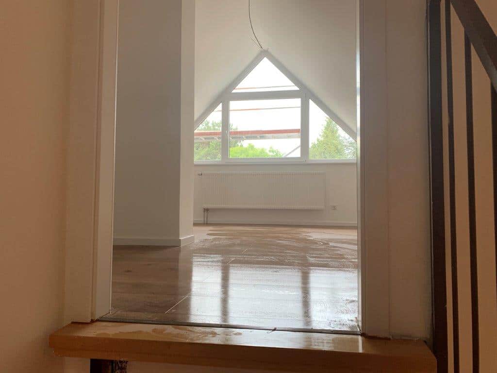 Blick durch die Tür in den sanierten Raum mit neuem Boden