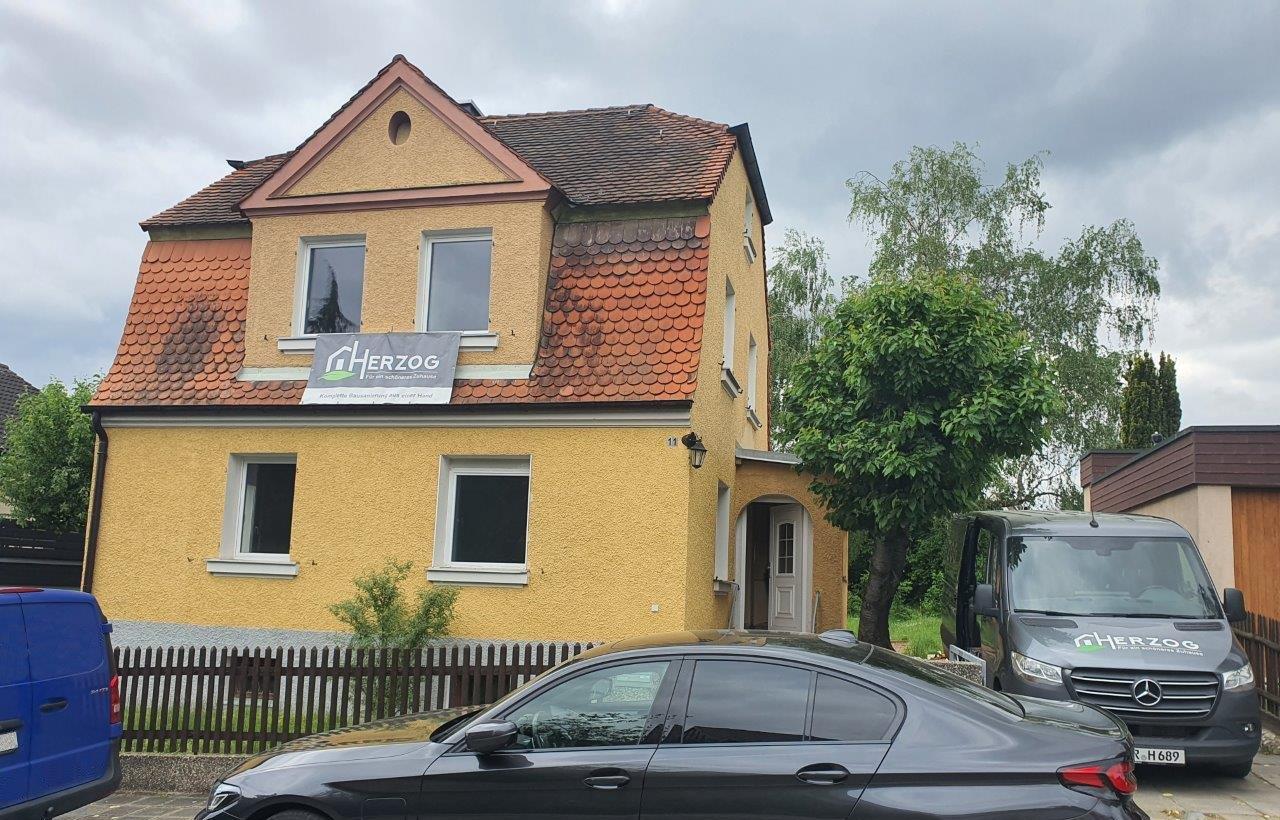Gelbes Mehrfamilienhaus in Zirndorf mit Herzog Schilder und Bau Lieferwagen davor