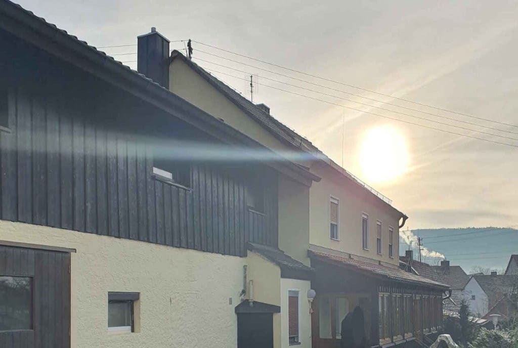 Bauernhaus-Komplettsanierung in Weigelshofen mit dunkler Holzfassade und hellem Putzfassade bei Sonnenuntergang