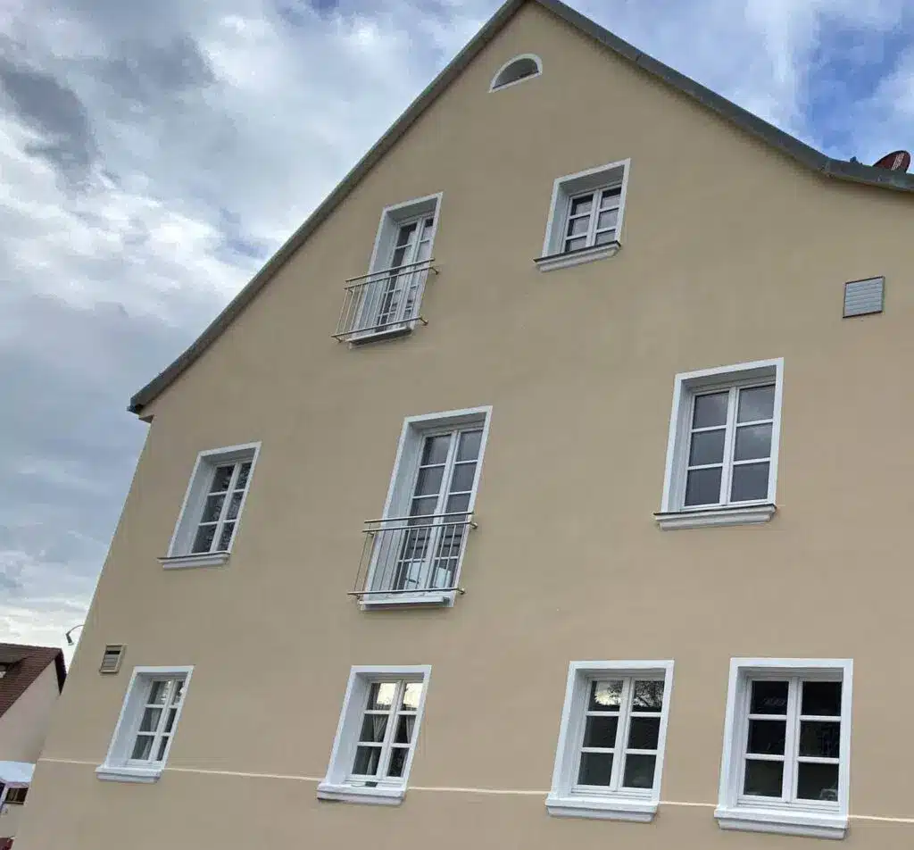 Fassade eines Gebäudes mit vielen Fenstern und kleinen Balkonen unter blauem Himmel