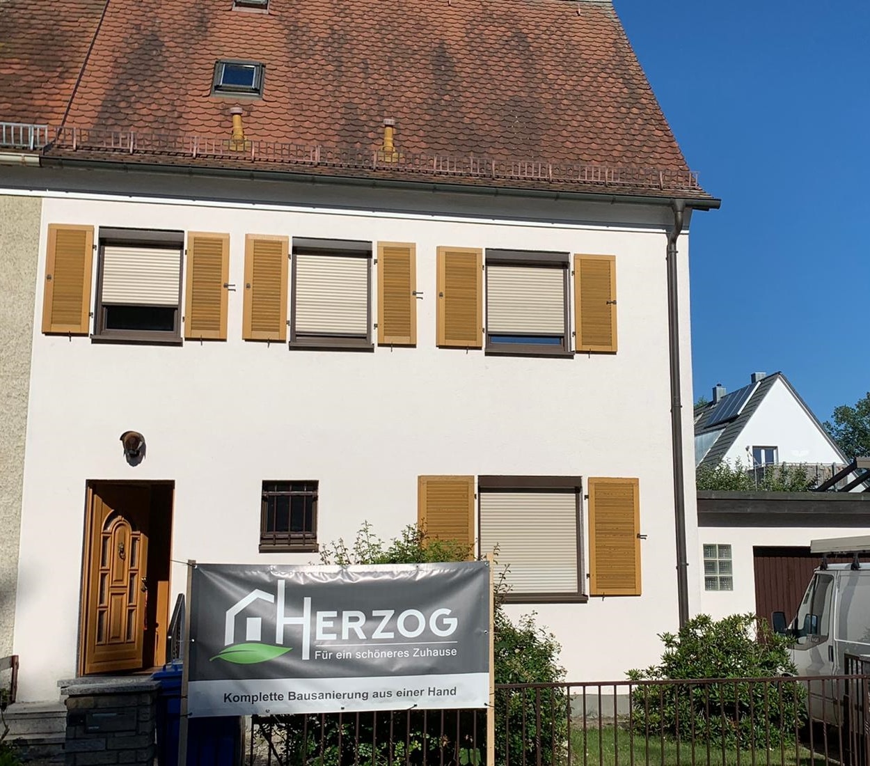 Außenansicht des teilsanierten Reihenhauses in Erlangen Süd mit herzog-bau Banner